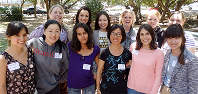 Eleven female internationals with female volunteer in a park.