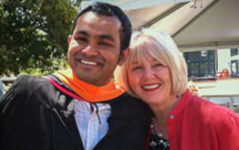 Female Homestay host with male international in his graduation robe.