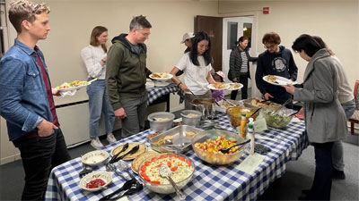 Diners serving themselves dinner from a table full of food